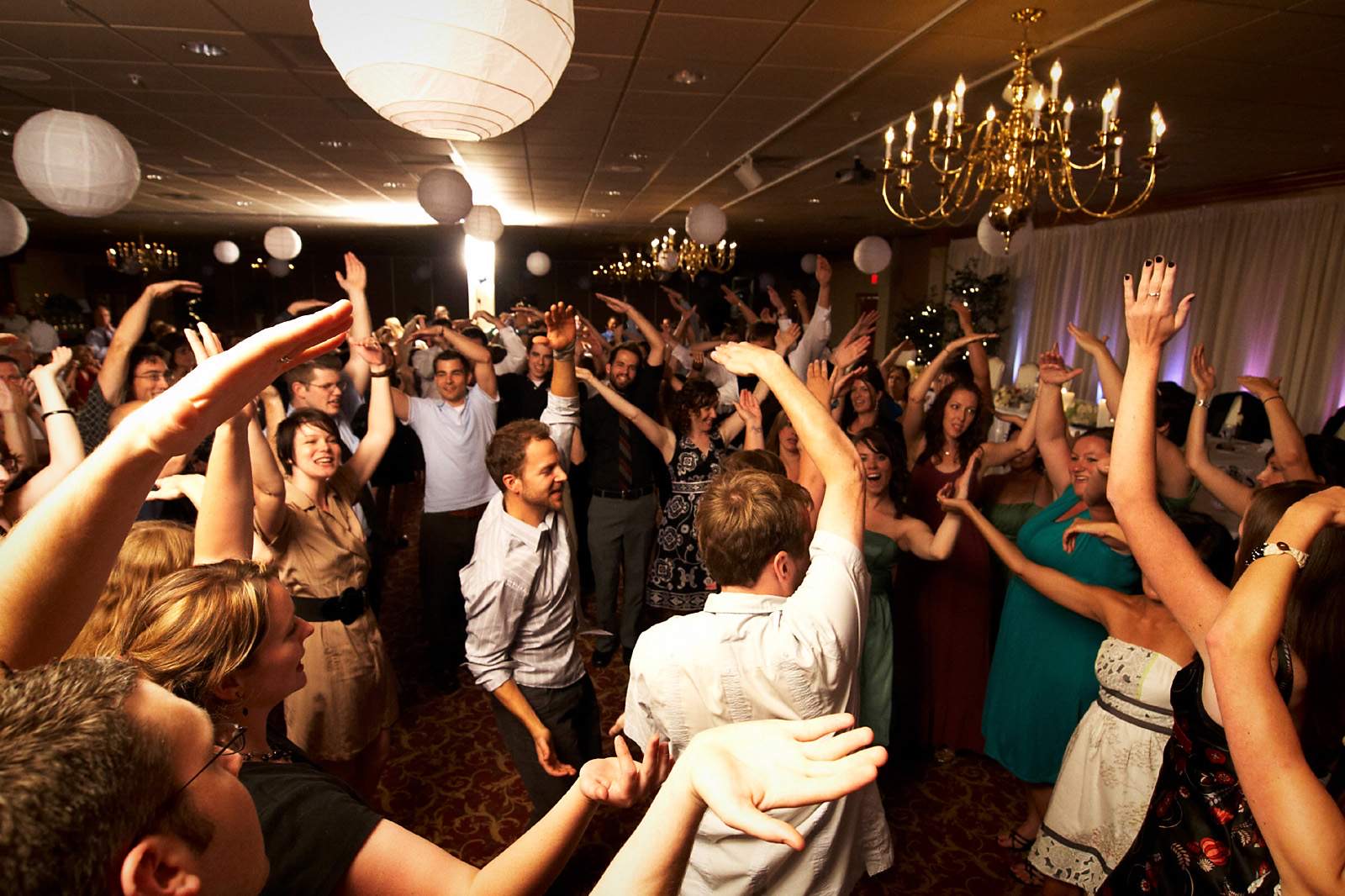 Wedding guests with their hands in the air on a packed dance floor